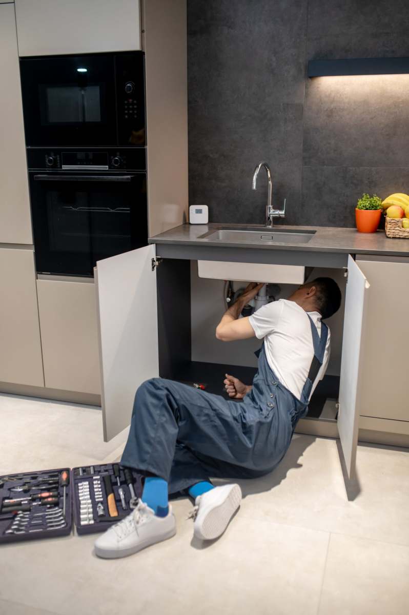man-reclining-looking-under-kitchen-sink-2023-11-27-05-17-52-utc